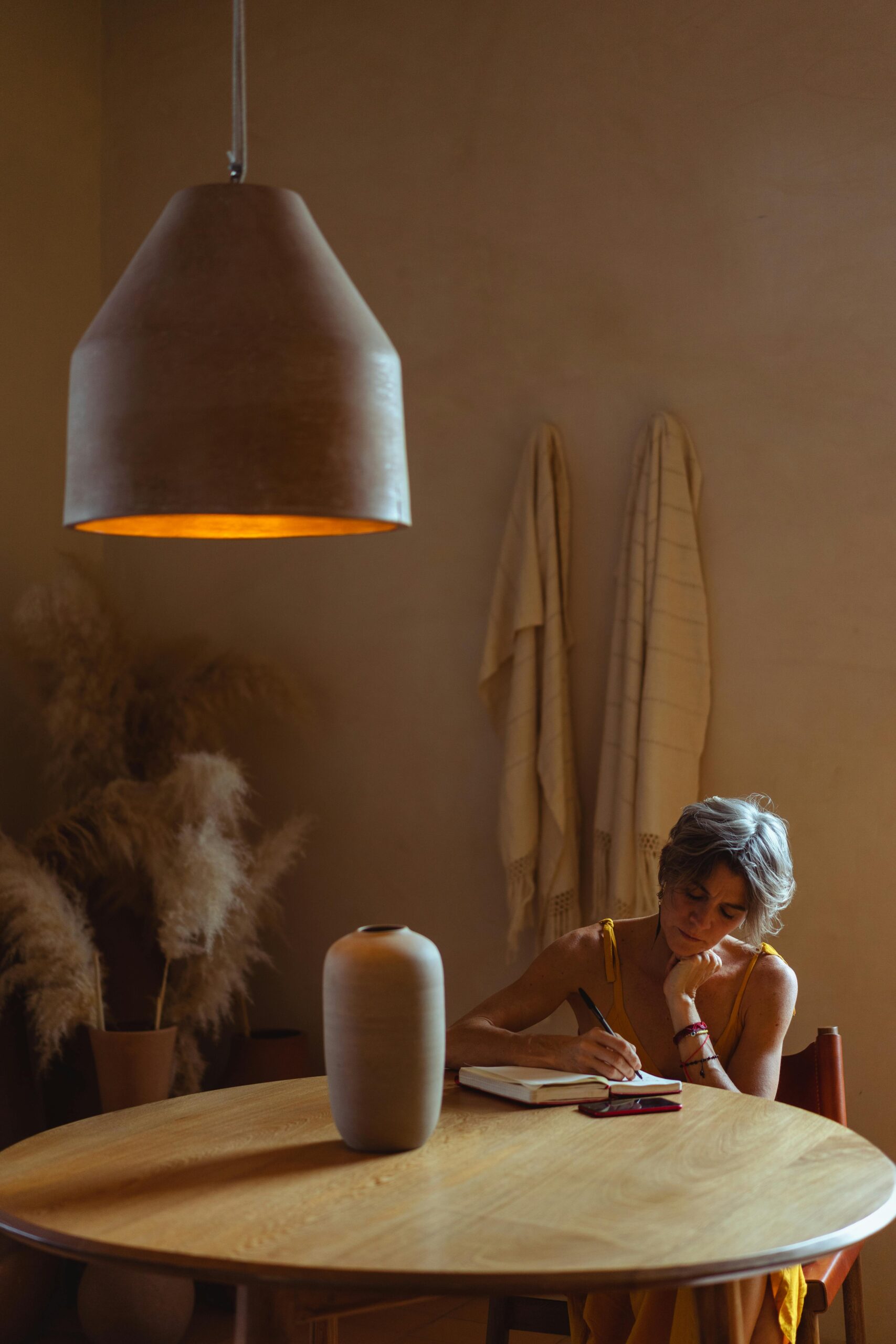 A woman sitting at a table, journaling her intentions, a key step in how to manifest your dream life.