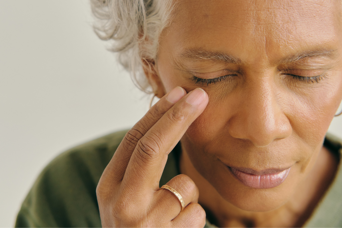 A close-up of a woman practicing EFT tapping by gently tapping under her eye to release stress and restore emotional balance.