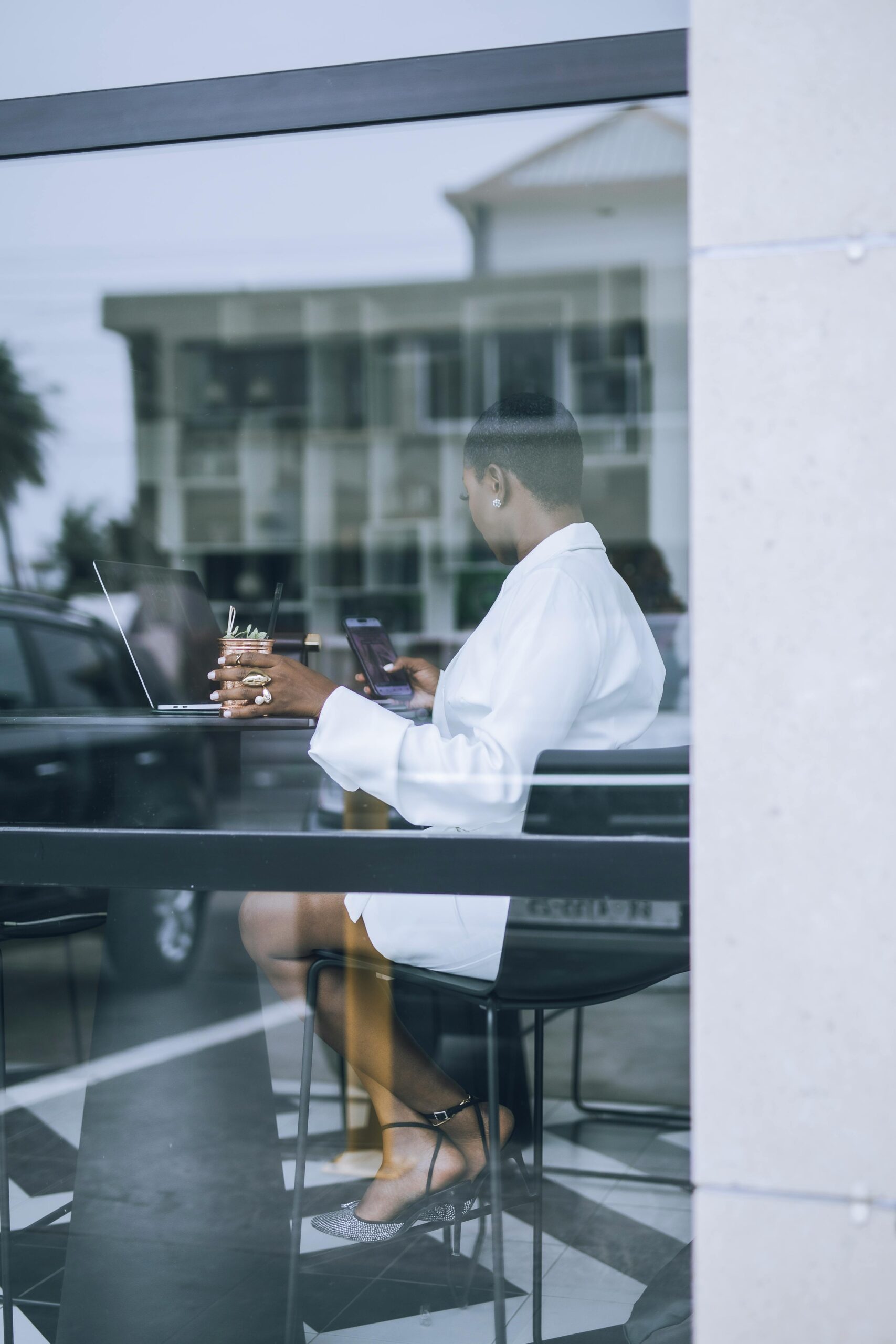 Successful woman working on her laptop at a café, enjoying coffee and embracing financial abundance and entrepreneurship.