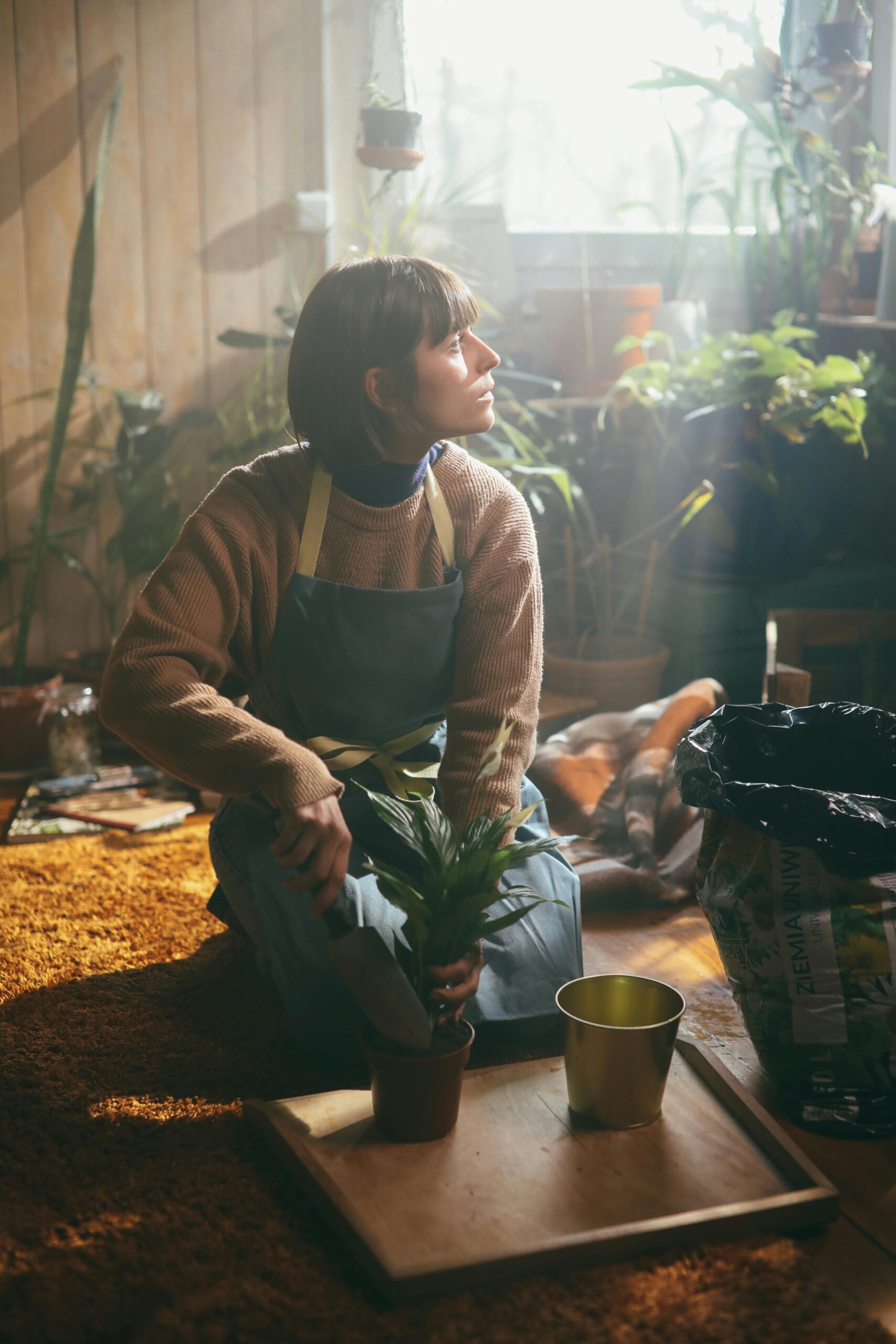 A serene woman gardening, looking up at the sun with a peaceful expression, embodying the essence of slow living and mindfulness.