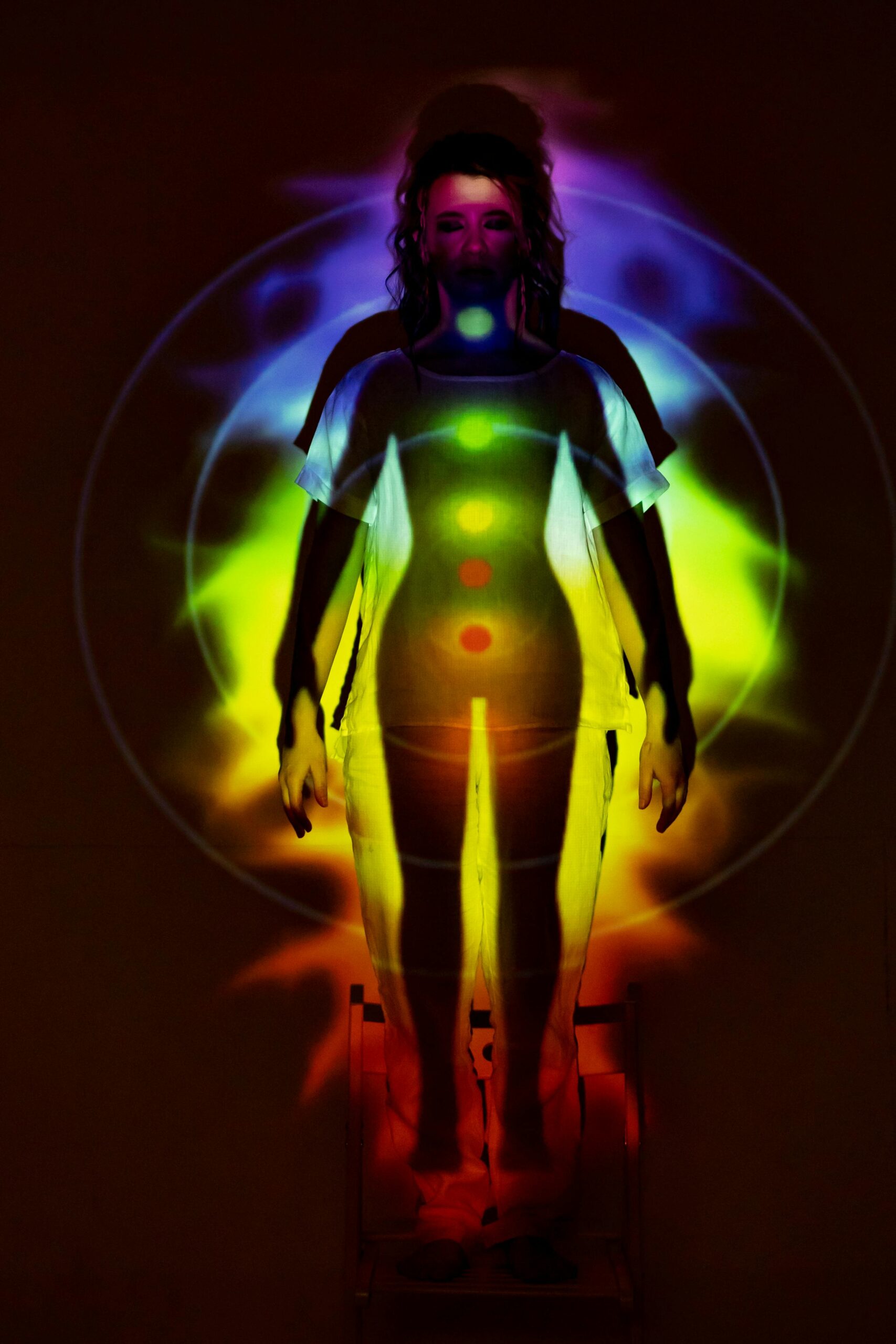 A woman with glowing chakra colors aligned along her body, representing the seven energy centers for chakra healing.