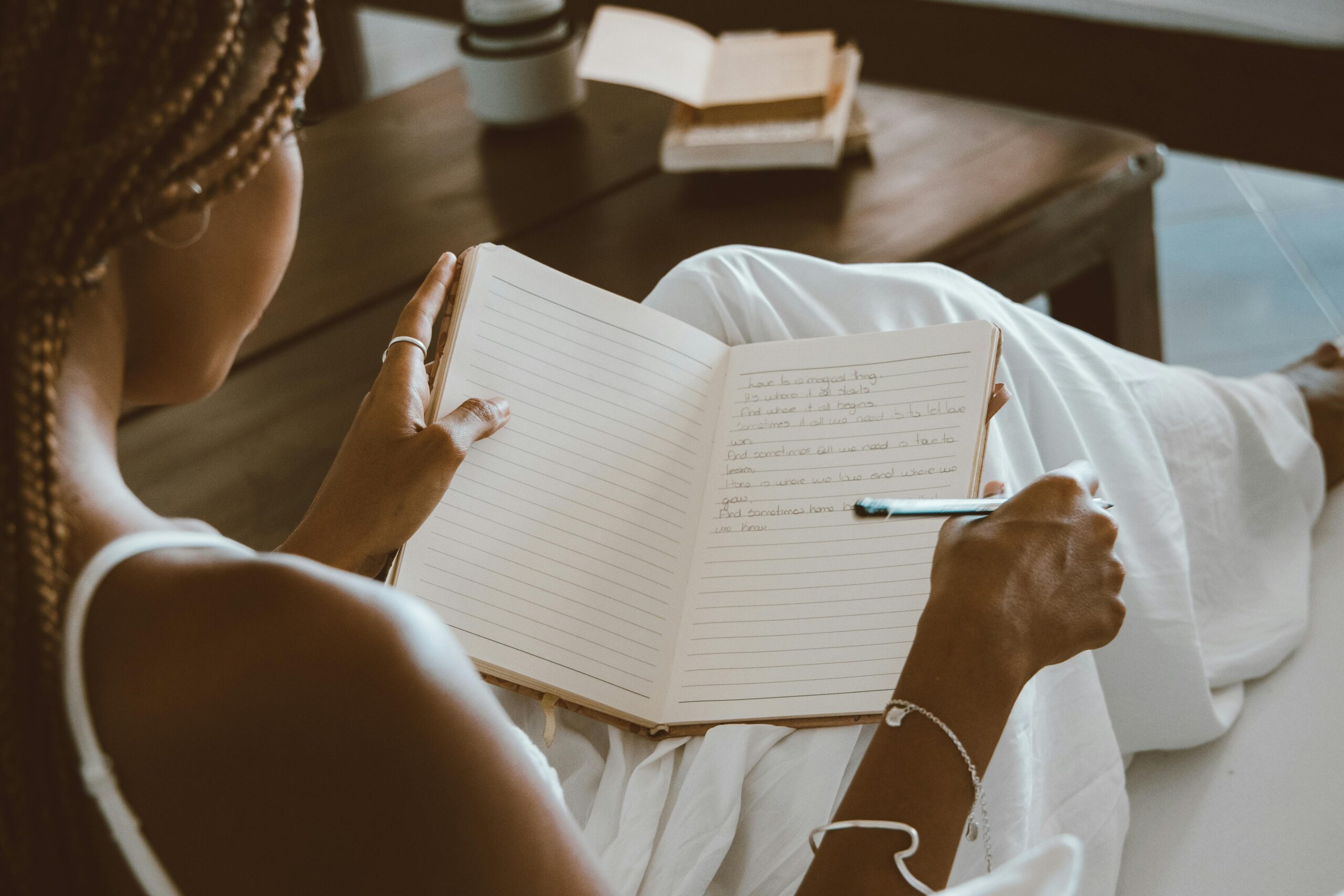 Woman journaling on her couch using journaling prompts for self-discovery.