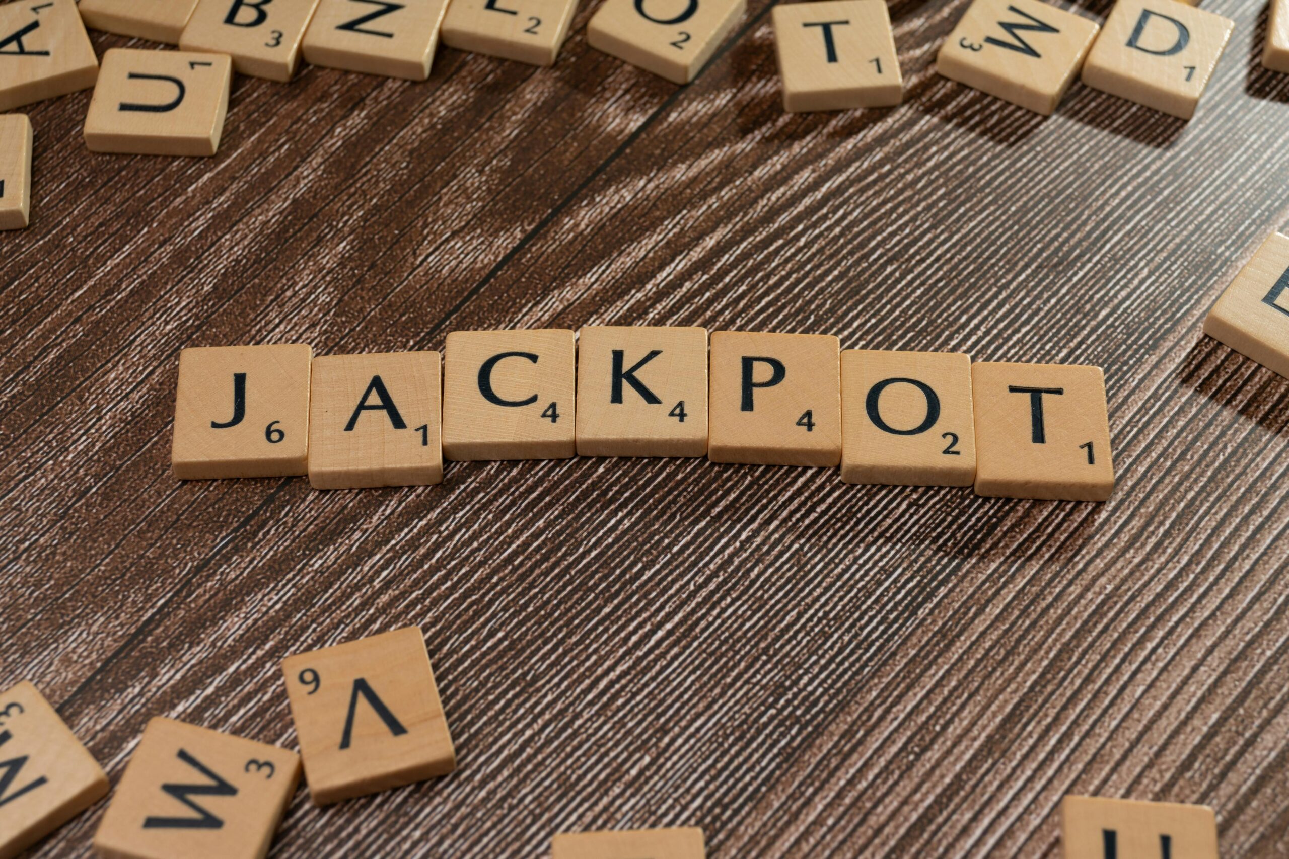 Wooden Scrabble-style tiles spelling out 'JACKPOT,' with numbers on each letter, symbolizing luck and lottery winnings.