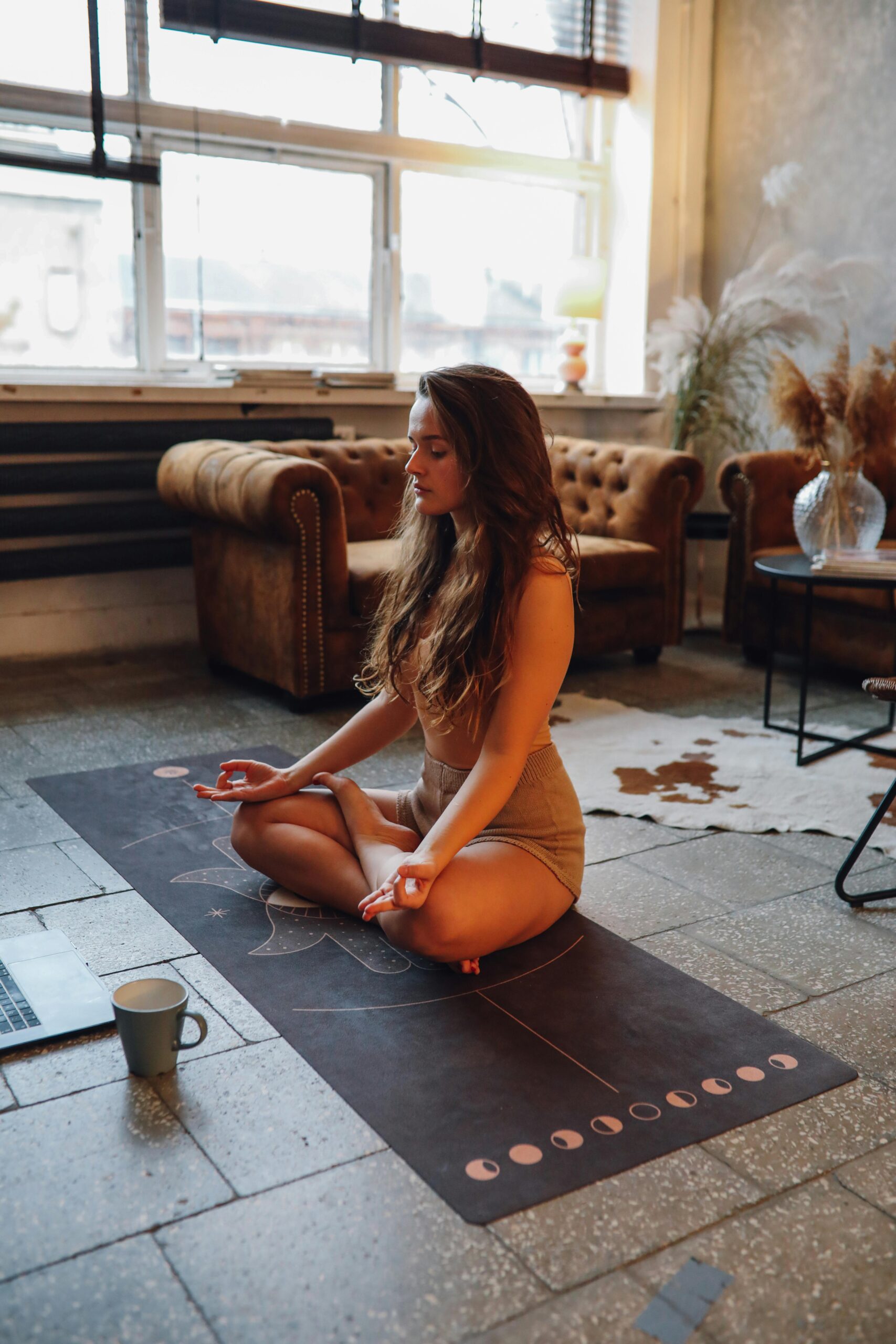 A woman meditating in a peaceful, decluttered room, embracing sacred spaces for energy alignment and relaxation.