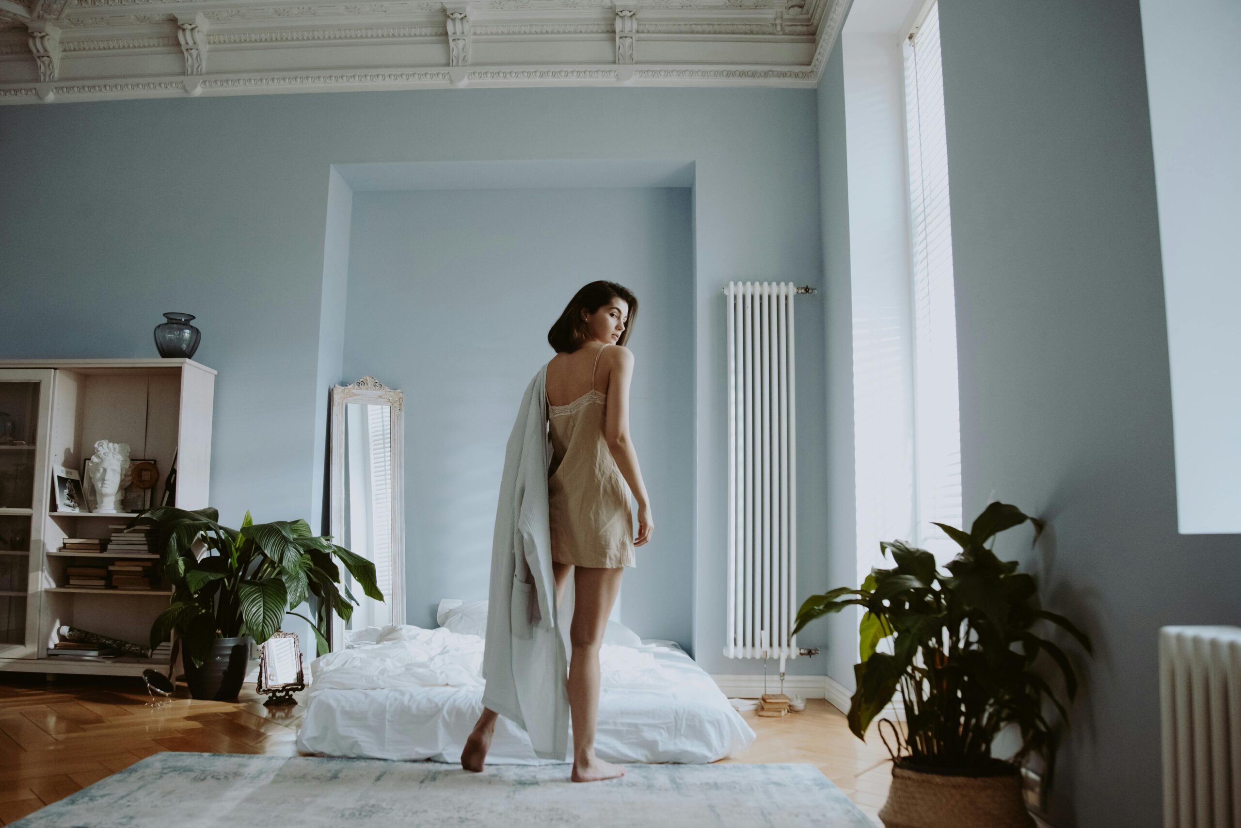 Woman in nightgown relaxing in her cozy bedroom during slow evenings, preparing for restful sleep.