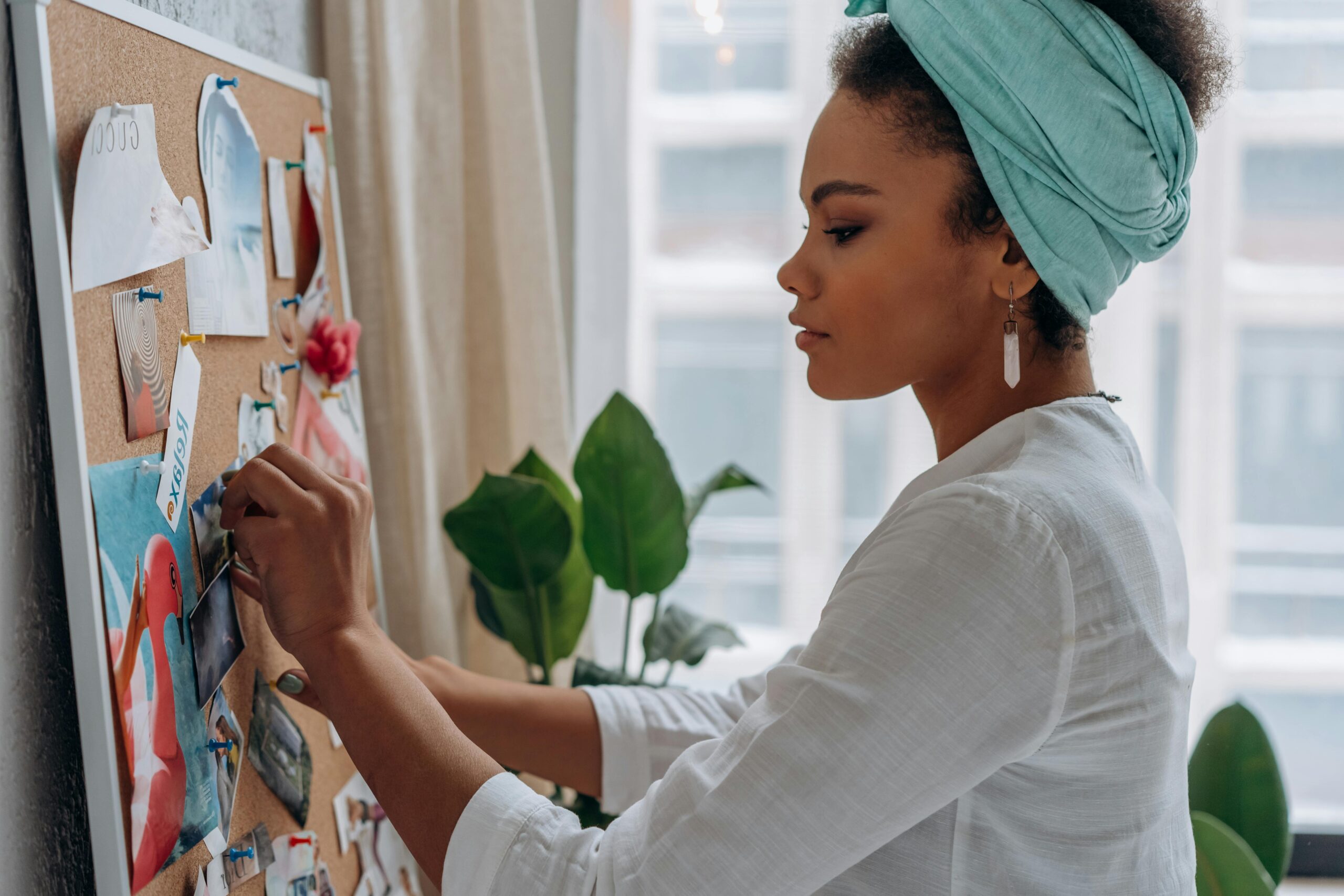 A woman adding a photo to her vision board, focusing on visualization for money mindset and manifesting financial abundance.