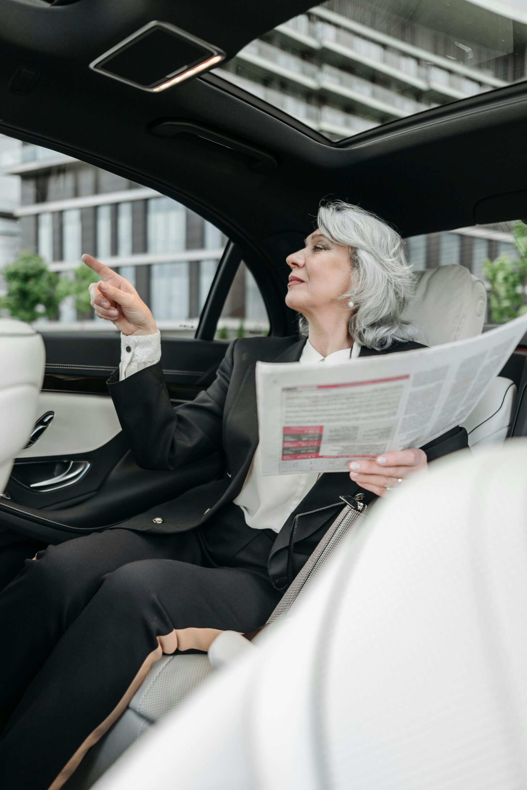 A confident, successful woman in a luxury car giving directions to her driver, embodying feminine energy for wealth and financial abundance.