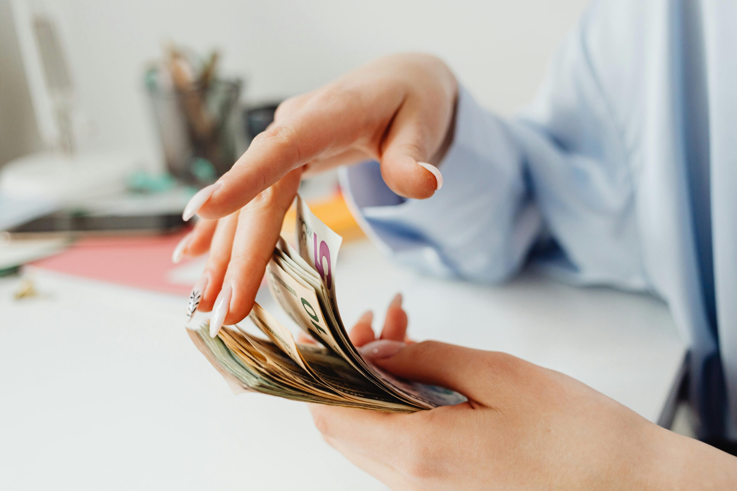 A woman's hand gently caressing a stack of money, symbolizing abundance and intentional money manifestation techniques.