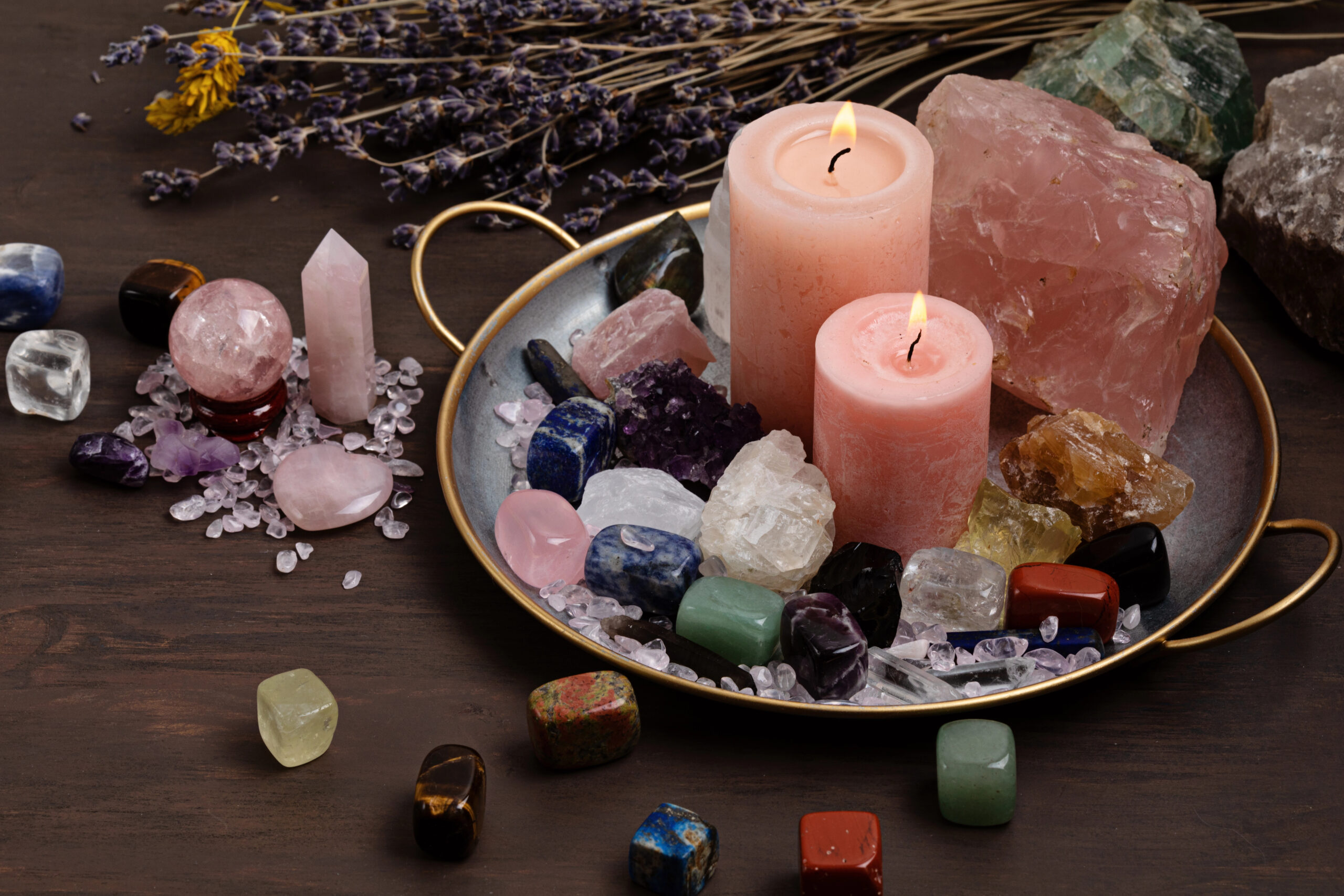 A calming flat lay of emotional healing crystals and candles on a wooden table, featuring rose quartz, amethyst, and clear quartz in a bowl surrounded by soft candlelight for spiritual healing and emotional balance.