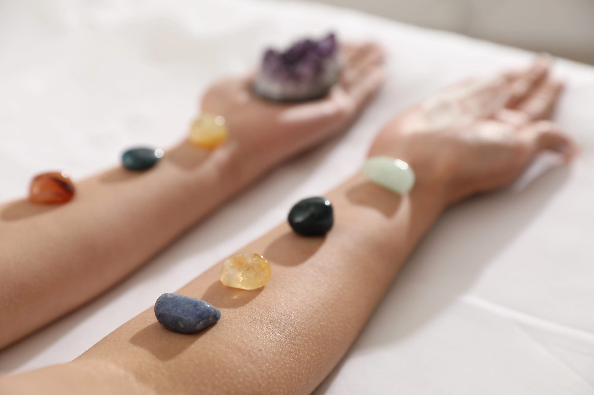 Woman with arms outstretched holding grounding crystals, symbolizing balance, calm, and connection to earth’s energy.